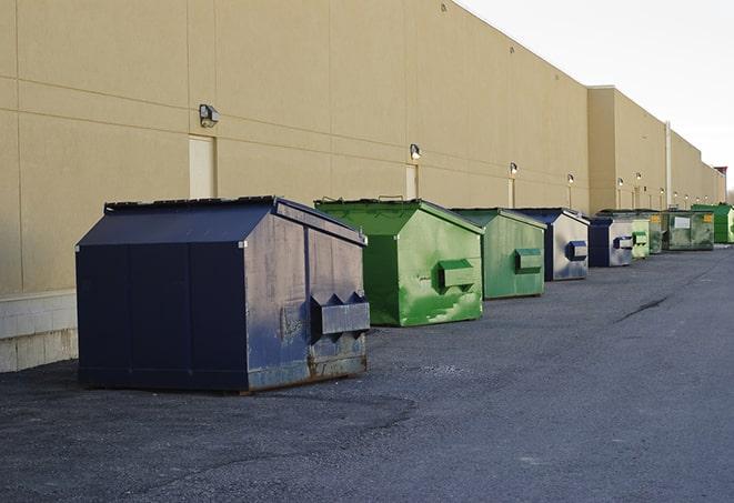 construction workers throw waste into a dumpster behind a building in Imboden AR